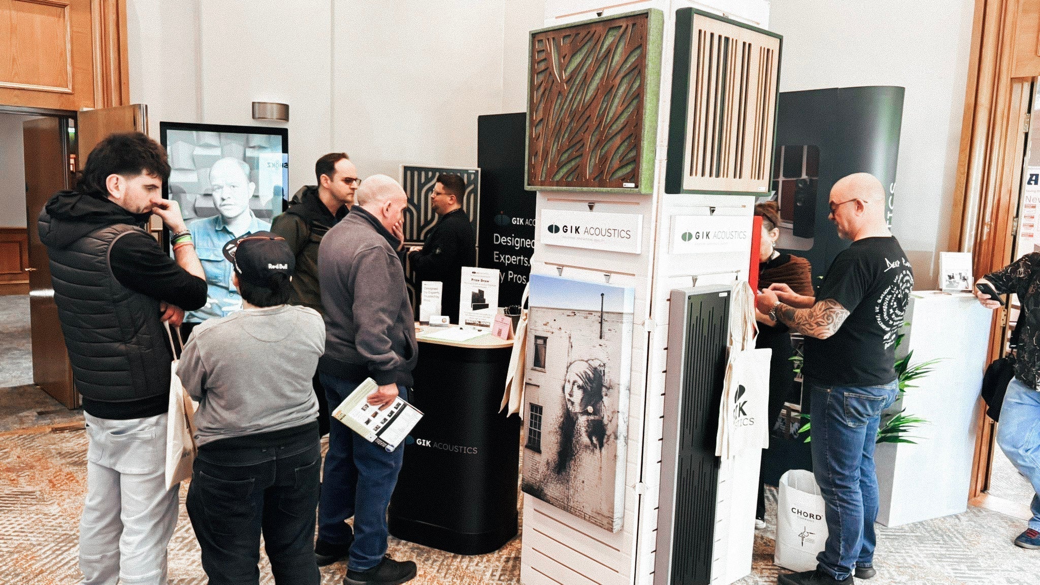Crowd of expo attendees at the GIK Acoustics booth featuring Amplitude Panels and Acoustic Art Panels