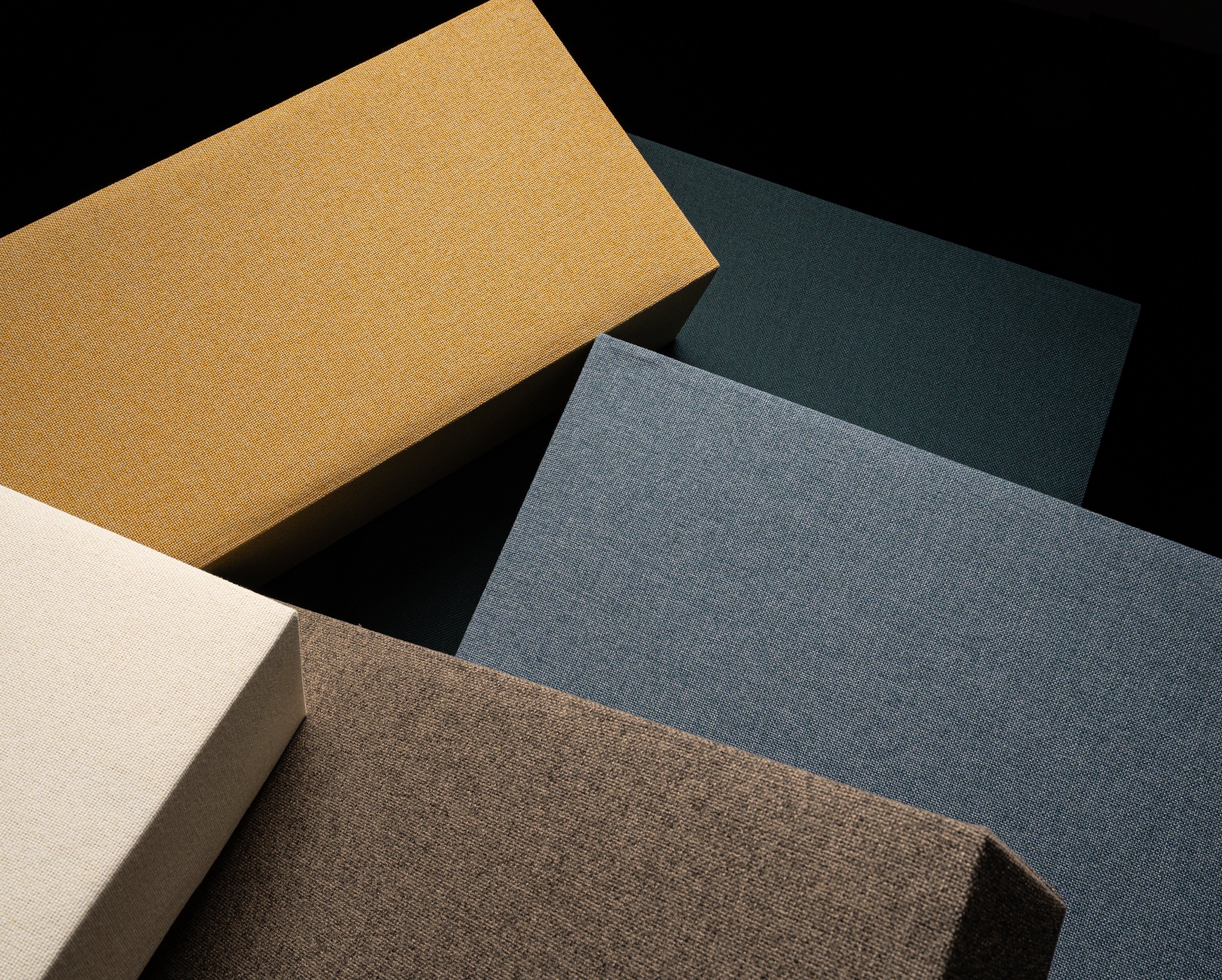 GIK Acoustics bass trap panels upholstered in Camira Cara fabrics, shown in multiple colors and arranged in an overlapping layout.