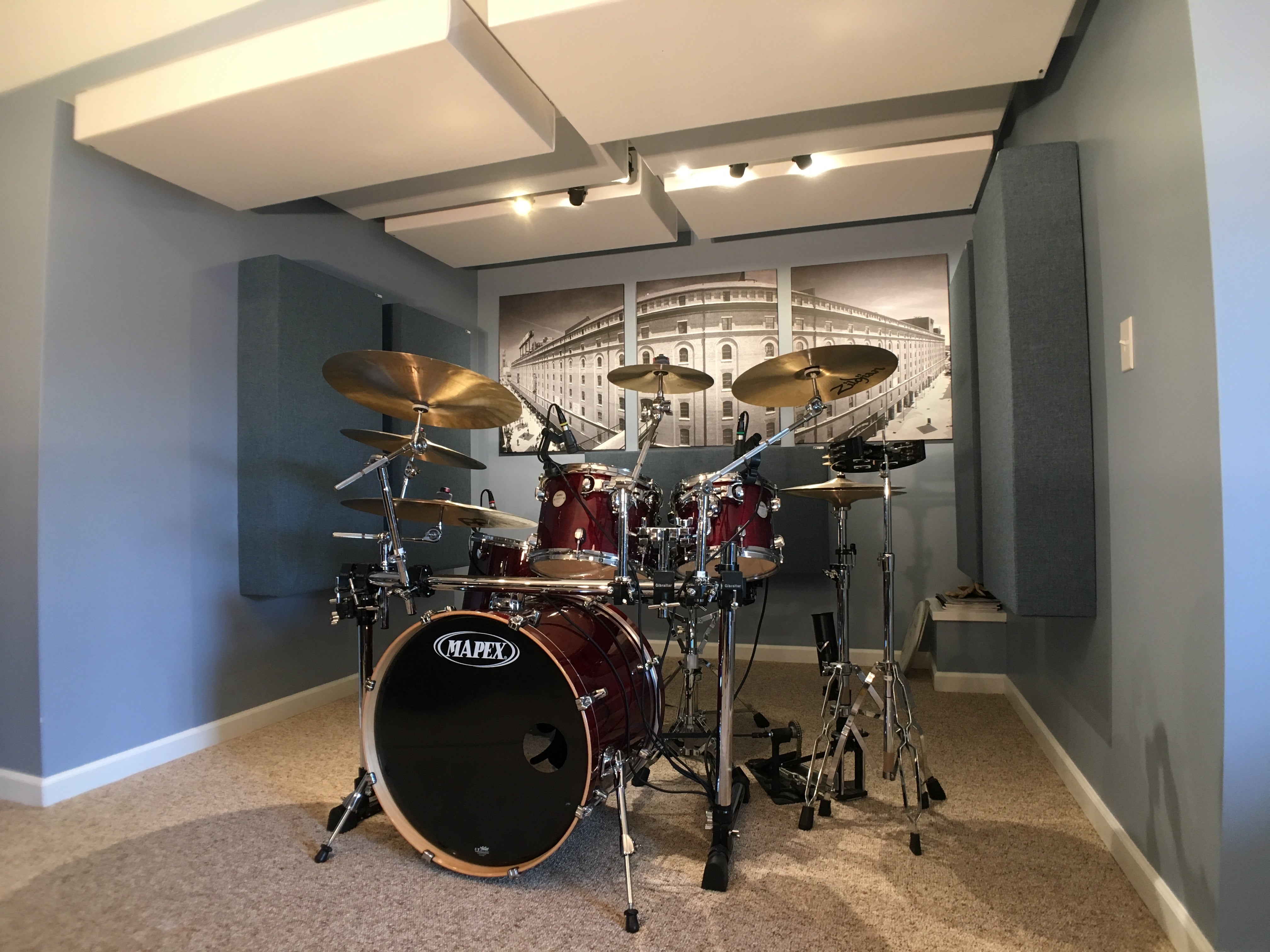  Drummer recording in a GIK Acoustics-treated room with bass traps and acoustic panels on the walls.