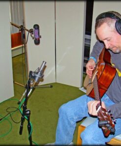 Musician playing guitar in a small recording space using portable acoustic panels for sound control.