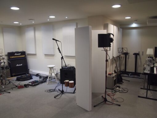 Music studio setup featuring instruments, microphones, and portable acoustic panels for vocal recording and noise reduction.