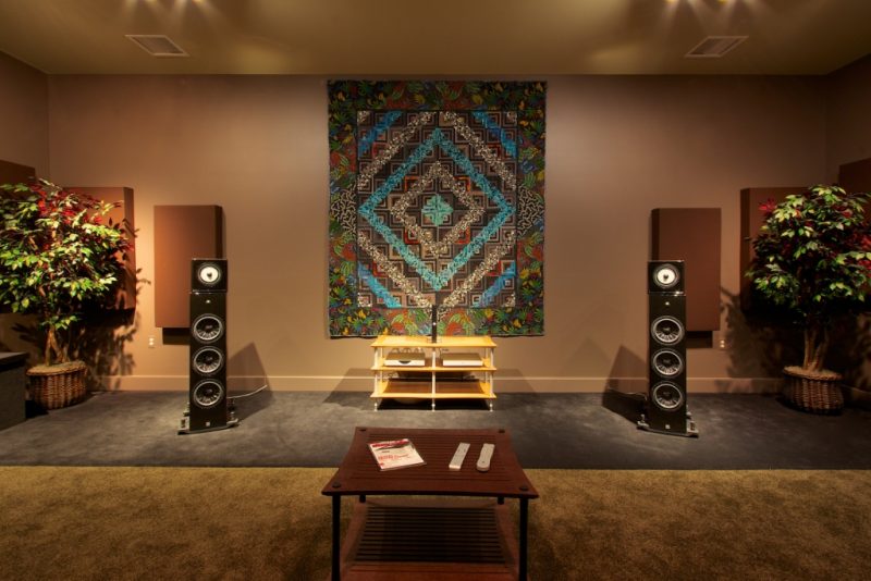 Listening room with large speakers, acoustic panels, and a colorful tapestry on the wall.